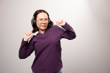 Young woman dancing and listening music in headphones on a white background