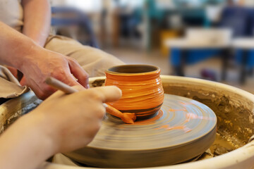 The Potter with student coloring a pot from clay on a Potter's wheel at workshop. Teaching pottery on a potter's wheel. Hobbies, craft and handwork. Healthy free time for children. Selective focus