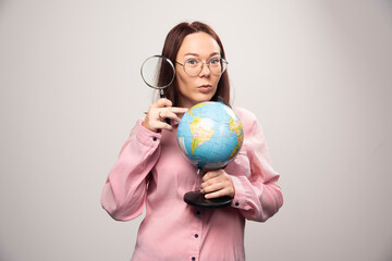 Portrait of woman holding a magnifying glass and Earth globe