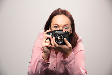 Woman taking a picture with camera on white background