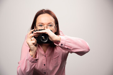 Woman taking a picture with camera on white background