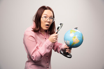 Portrait of woman holding a magnifying glass and Earth globe