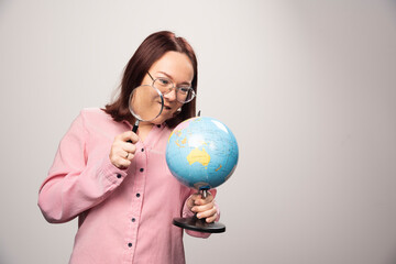 Portrait of woman holding a magnifying glass and Earth globe