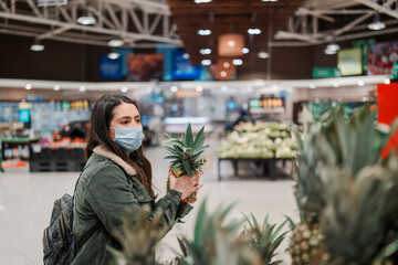 latin woman with face mask in a supermarket buying groceries or fruits