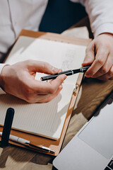 A middle-aged family doctor with a beard works in a clinic. A successful senior doctor in a white lab coat writes down the data in a notebook.