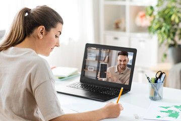 school, education and distance learning concept - female student with teacher on laptop computer screen having video call or online class at home