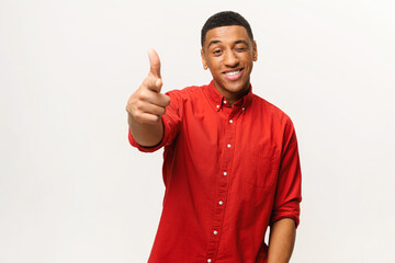 Portrait of man wearing red casual style shirt, pointing finger pistols to camera playfully and flirting, choosing lucky winner. Indoor studio shot isolated on white background