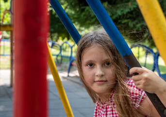 Deep look of big brown eyes of teenager girl on blurred background of kid swing