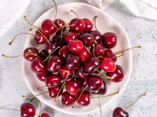Naklejka na ściany i meble Fresh cherry. Ripe cherries in a plate on a stone background. Bulk cherries. close up