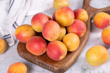Fresh apricots. Ripe apricots in wooden serving platter on stone background. Bulk apricots. close up