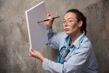 Woman artist shows her canvas with brush on marble background