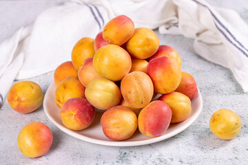 Fresh apricots. Ripe apricots in a plate on a stone background. Bulk apricots. close up