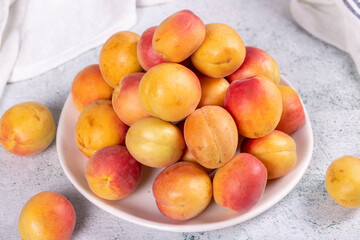 Fototapeta na wymiar Fresh apricots. Ripe apricots in a plate on a stone background. Bulk apricots. close up