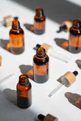 Open amber bottle with serum or essential oil. Pipettes with bamboo cap. White background with daylight and beautiful shadows. Beauty concept for face and body care