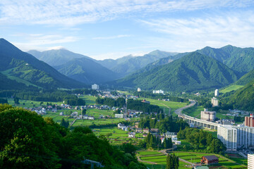 関越高速道路のS字カーブが特徴的な米処湯沢の春の田園風景とリゾートマンション群
