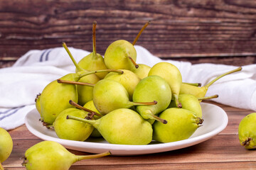 Fresh pear. Ripe pears in plate on wood background. Bulk pear. close up