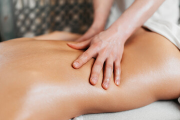 Beautiful young woman receiving professional body massage treatment with aromatherapy essential oil.