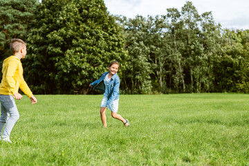 Fototapeta premium childhood, leisure and people concept - happy kids playing tag game and running at park