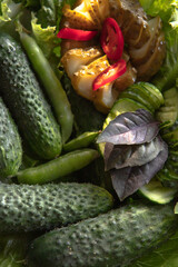 Fresh organic cucumbers in a sieve and herbs on a dark wooden background. Preparing for pickling.