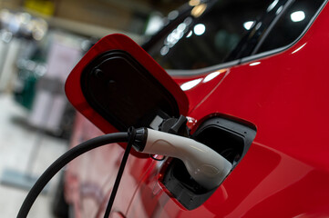 Closeup of power supply plugged into an modern electric car. Electric or EV car charging station.