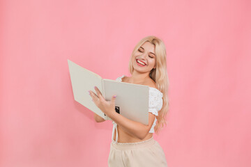 beautiful girl in light clothes with a book in her hands on a pink background