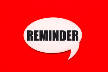 On a bright red background, a light wooden curly card with the text REMINDER