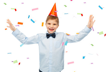 birthday, childhood and people concept - portrait of smiling little boy in party hat and bowtie over confetti on background