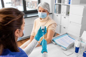medicine, health and vaccination concept - doctor or nurse filling syringe with vaccine or drug and...