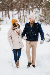 Fototapeta na wymiar people, love and leisure concept - happy smiling couple walking in winter forest