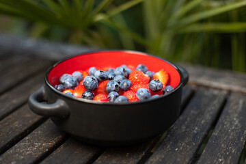 bol de fruits rouges, myrtilles, fraises et framboises posé sur une table. Alimentation saine pour être en bonne santé et perdre du poids