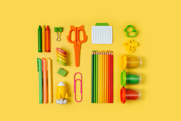 Kids stationery is arranged neatly on yellow background. Primary School stationery supplies. Workplace organization. Concept back to school.