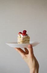hand holding a plate with Napoleon cake with fresh berries - 515630884