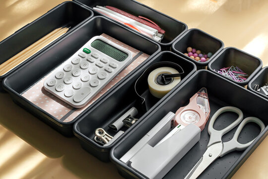 Stylish  stationery  is arranged in black organizers. Creative Drawer Organizing. Storage office supplies.
