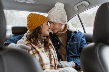 people, love and leisure concept - happy smiling couple hugging and rubbing noses on car back seat...