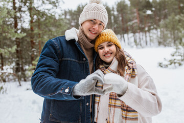 people, love and leisure concept - happy smiling couple making hand heart gesture in winter park