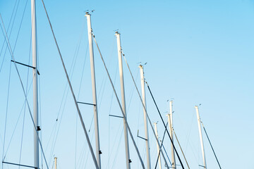 Masts of sailing yachts against the blue sky. Sea background pattern.