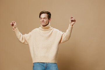 a happy, joyful young man with red hair, in a long sweater, dances merrily. Studio photography on a plain background with empty space for an advertising layout