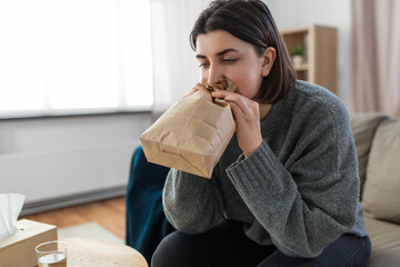 mental health and psychological problem concept - woman having panic attack breathing to bag at home