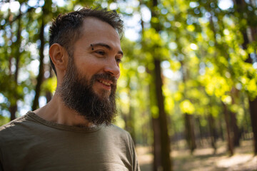 Side view of young bearded male outdoor in summer forest.