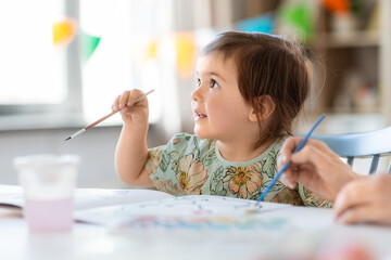 childhood, art and leisure concept - little baby girl drawing at home or kindergarten