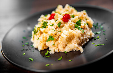 Risotto with mushrooms in a black plate on wooden background