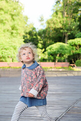 Portrait of a pretty confident little girl in a summer park