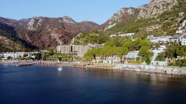 Panoramic drone view of seaside and beach in resort village Turunc in Turkey. Resort embankment view from sea. Touristic resort town surrounded by mountains