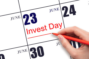 Hand drawing red line and writing the text Invest Day on calendar date June 23. Business and financial concept.