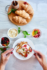 Woman hand eating breakfast of french toast with strawberries and maple syrup, good morning..