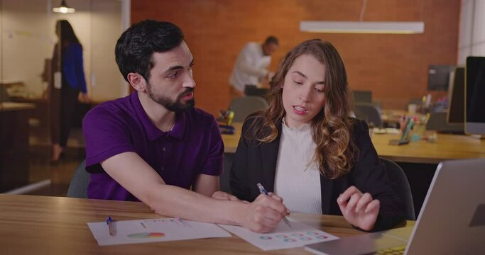 Two millennials employees at office meeting together. Female and male staff discussing work at office workplace