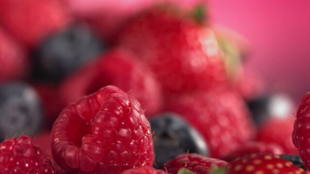Ripe juicy Strawberry Blueberry Raspberry rolling above many mixed Berries