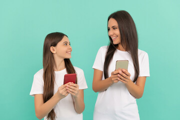 happy mother and daughter surfing internet on smartphone on blue background