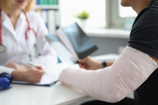 Doctor conducts medical consultation with patient with cast on arm