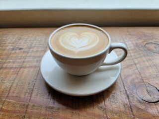 나무테이블 위 하트로 데코레이션된 라떼와 풍경